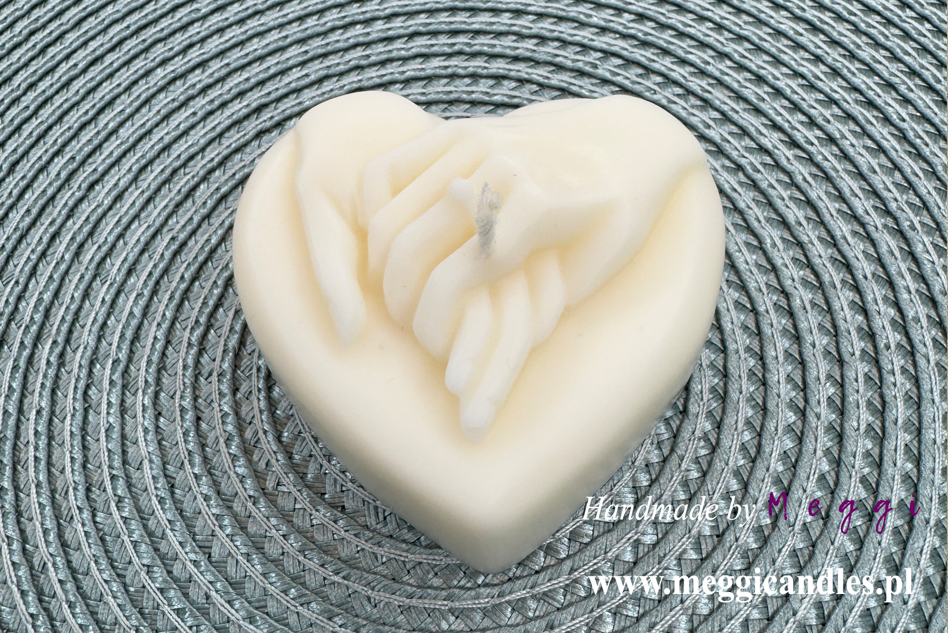 Świeca sojowa Meggi Serce ze splecionymi dłońmi na materiałowej podkładce